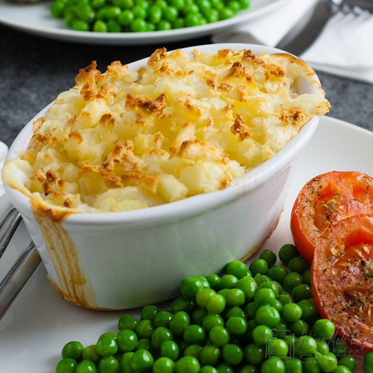easy fish pie on a plate with peas and tomatoes