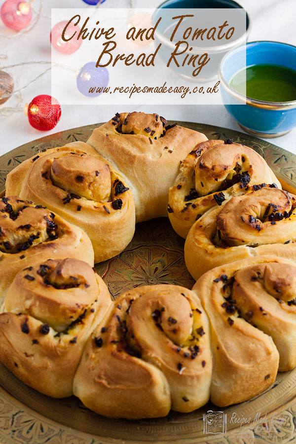 Chive and tomato bread ring on a serving plate with oil and vinegar bowls behind