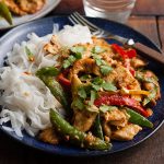 plate of nutty chicken stir fry with noodles and fork on the side