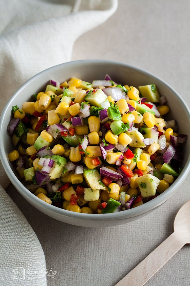 bowl of avocado and sweetcorn salad with spoon by the bowl.