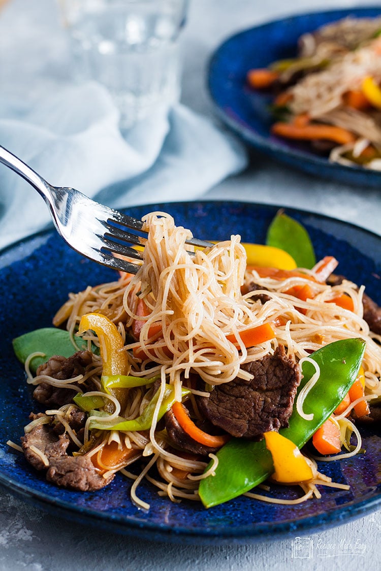 serving of beef stir-fry with rice noodles on a fork.