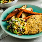oven baked chicken schnitzel on plate with salsa and chips.
