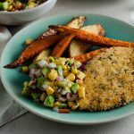 oven baked pork schnitzel served with salsa and potato wedges.