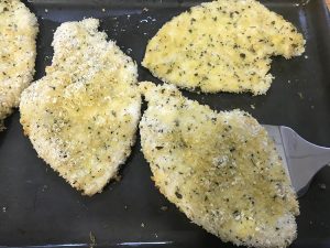 part cooked chicken schnitzel on a baking sheet.