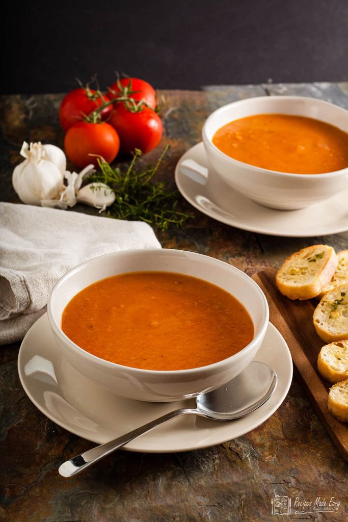 bowls of roasted tomato soup with coutons on the side