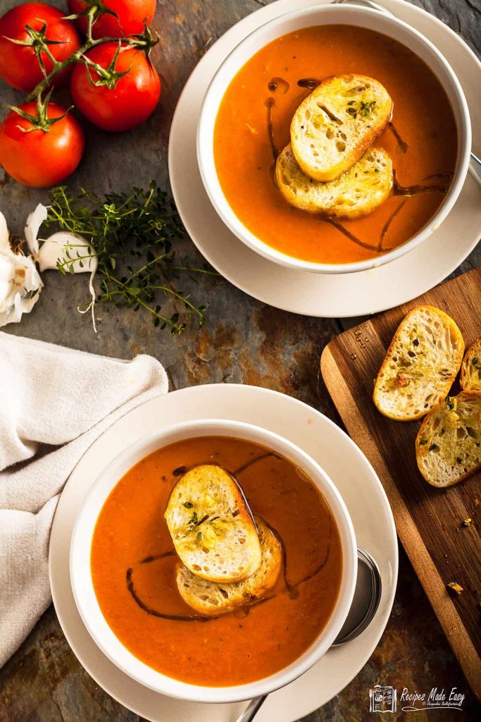 two bowls of roasted tomato soup topped with thyme croutons.