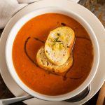 bowl of roasted tomato soup with thyme croutons on top