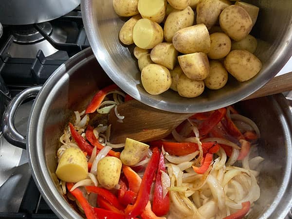 adding potatoes to the pan.