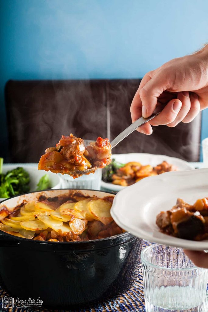 serving a portion of beany lamb casserole from pot