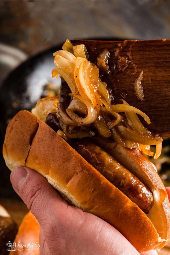 spooning onion into hot dog.