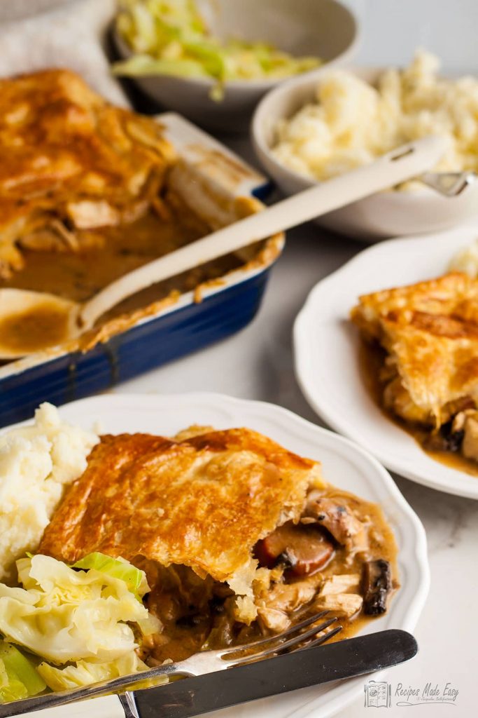 Two servings of turkey and chorizo pot pie on plates. with remaining pie behind.