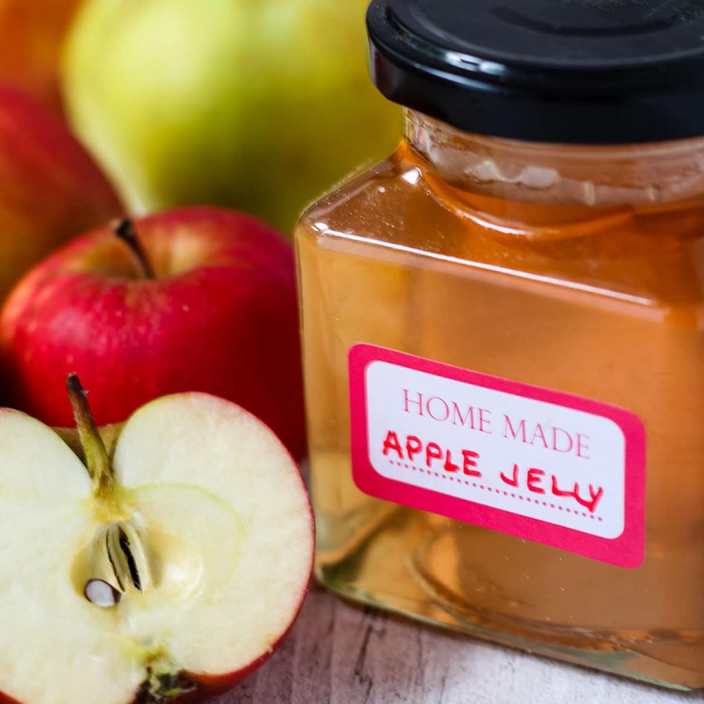 jar of apple jelly with apple to the side.