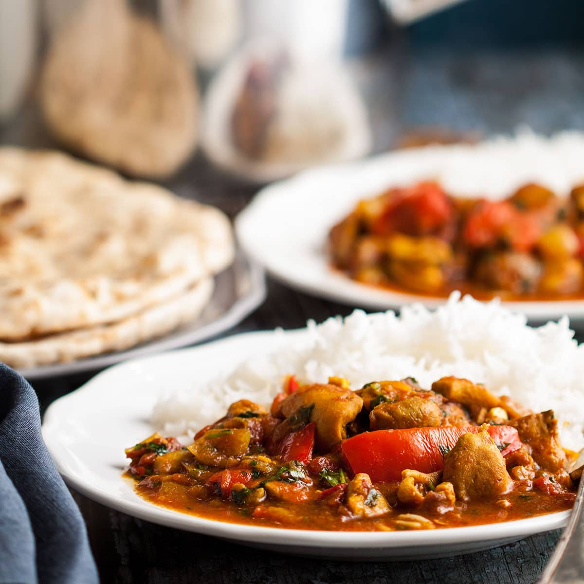 two plates of spicy chicken curry served with rice.