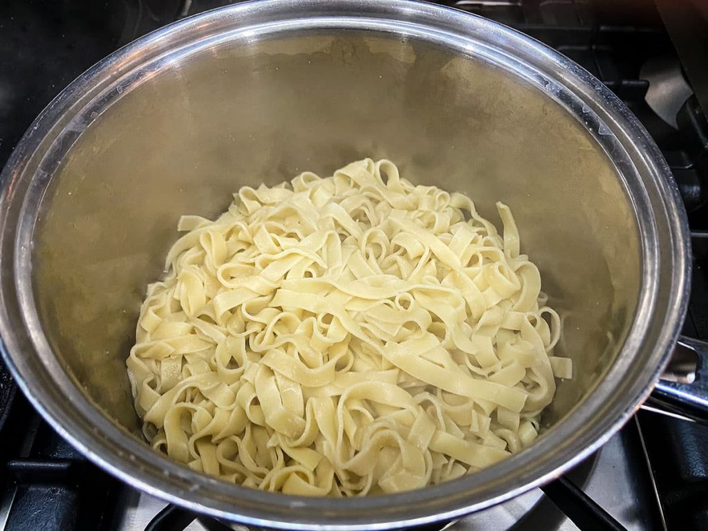 Drained tagliatelle in a saucepan.