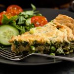 portion of pea and spring onion frittata on a plate with some salad.