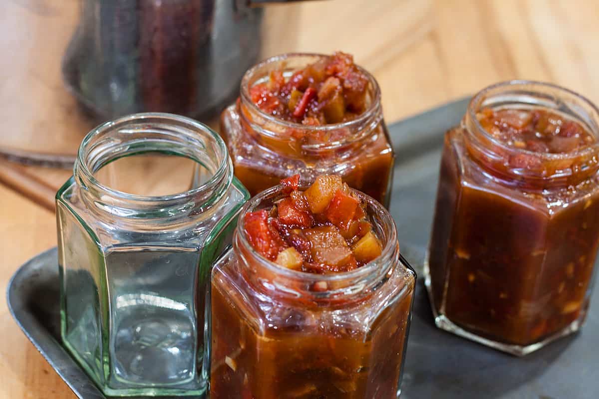 tomato chutney packed into 3 of 4 jars ready for sealing.