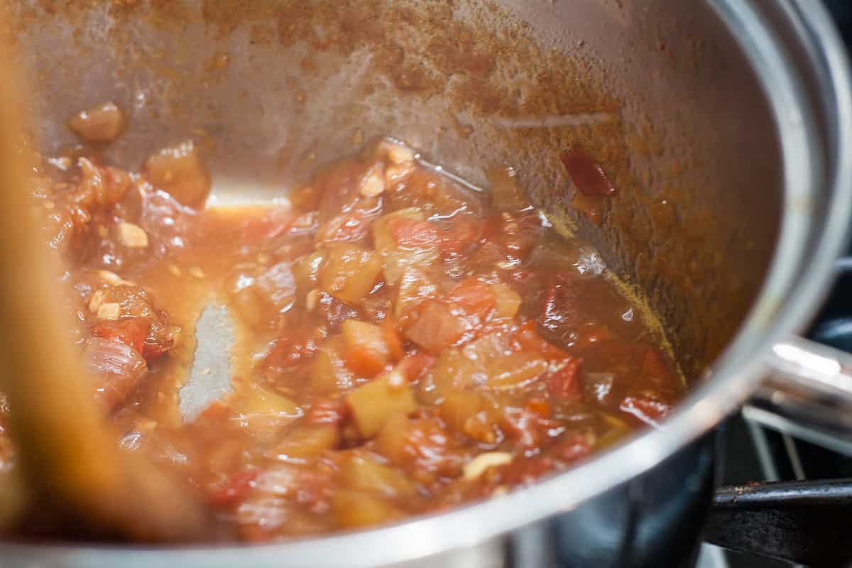 tomtato chutney in pan showing channel left by wooden spoon when ready to pot.