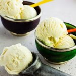 two bowls and icecream scoop filled with basil ice cream