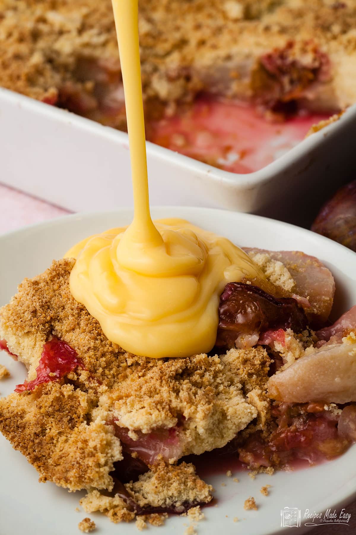 custard pouring onto a plate of fruit crumble.
