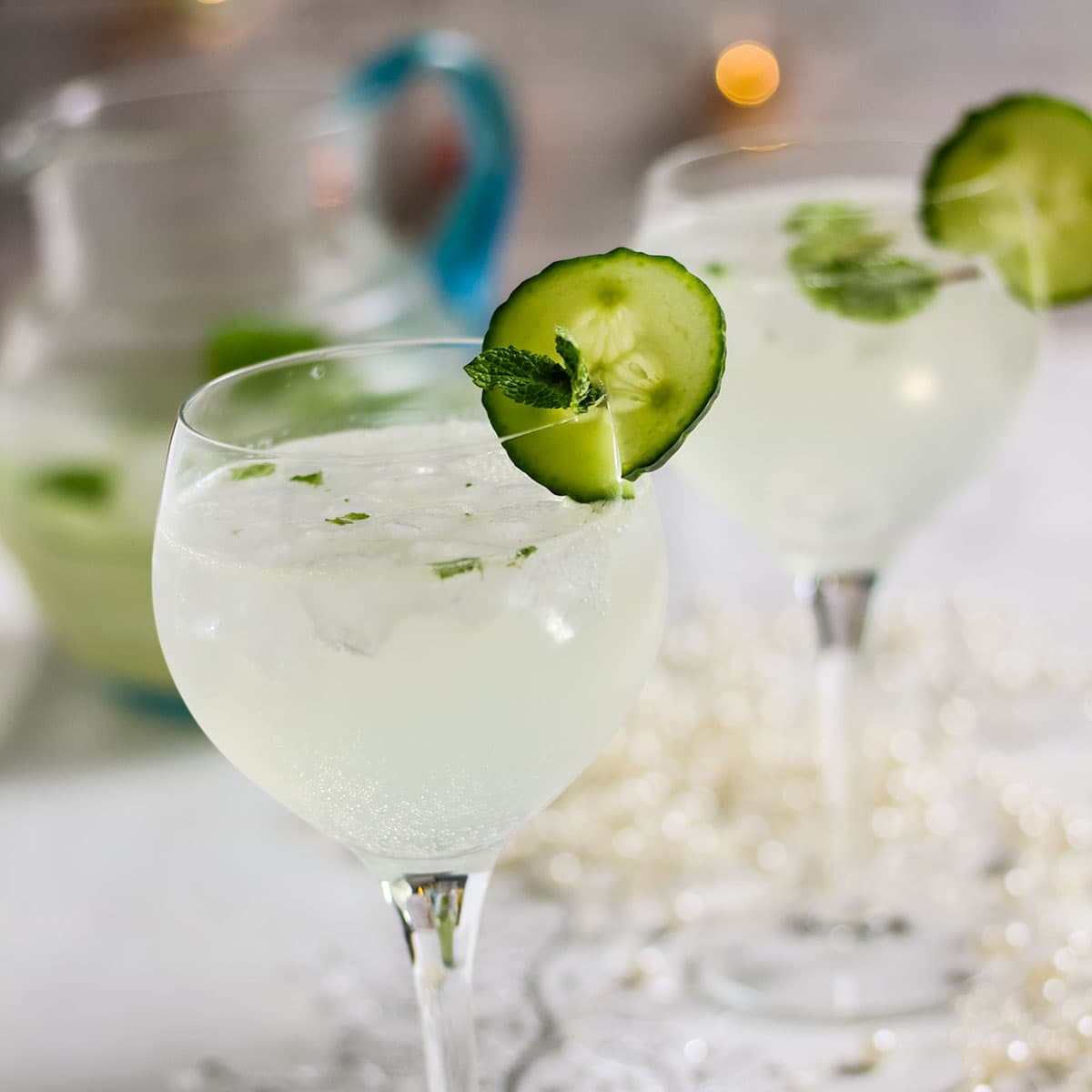 2 glassesglasses of lime and mint spritzer with jug behind.