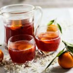 jug andtwo glasses of mulled cranberry and clementine punch on a festive table.