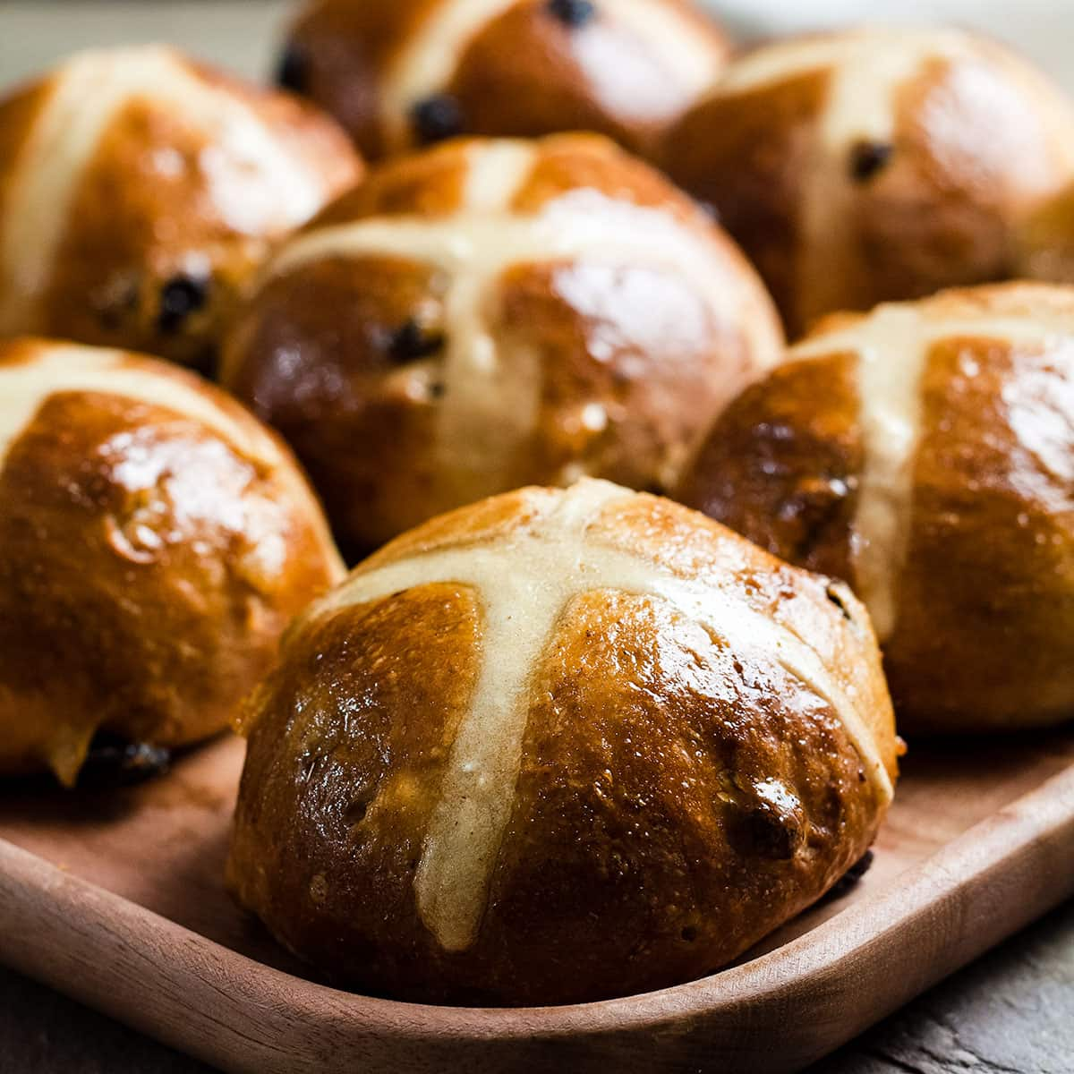 sourdough hot cross buns on a wooden platter