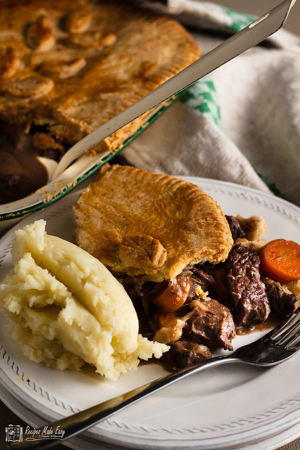 portion of steak and red wine pie on a plate with mash potatoes. wh
