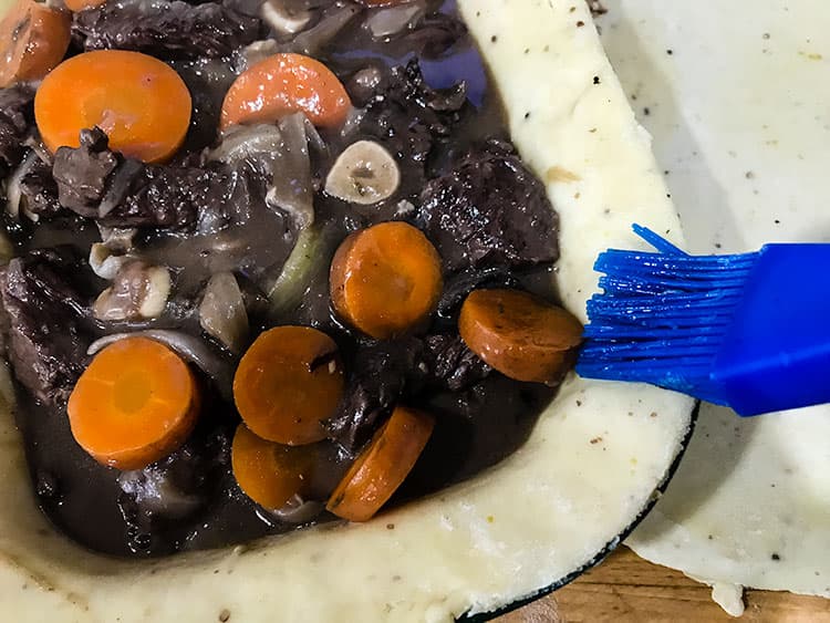 brushing the edges of an uncovered pie with egg wash.uncovered pie