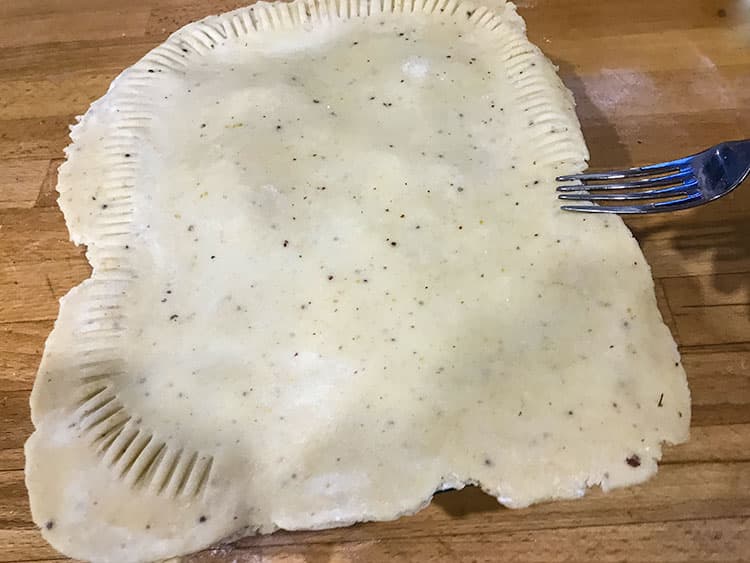 seling edge of pie with fork before trimming.