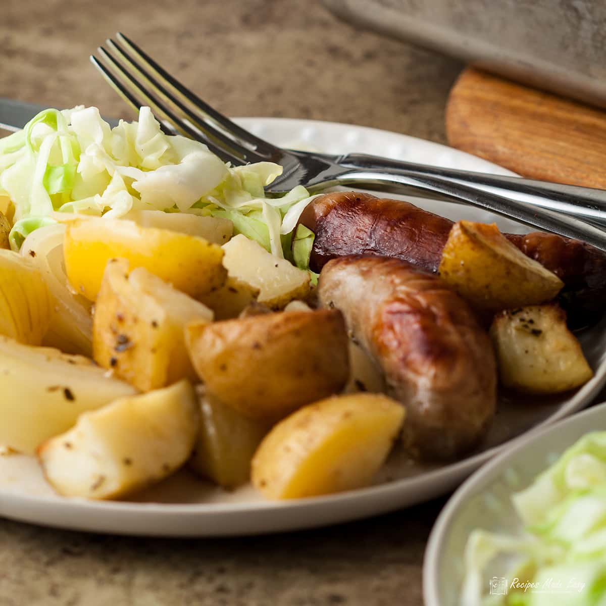 portion of sausage and apple casserole on plate with knife and fork