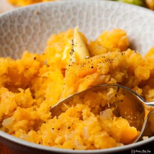 closeup of mashed swede in serving bowl, with spoon.