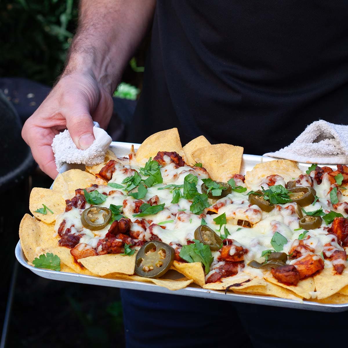 person holding tray of easy chicken nachos.